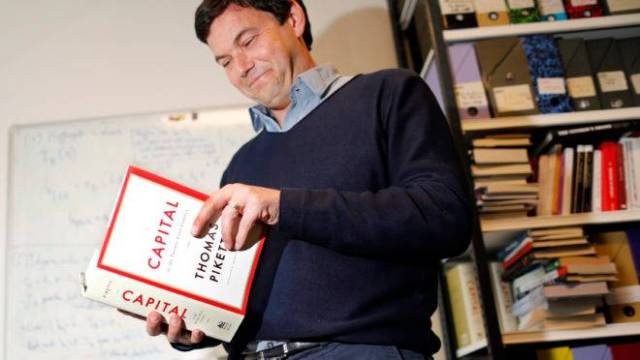 French economist and academic Thomas Piketty, poses in his book-lined office at the French School for Advanced Studies in the Social Sciences (EHESS), in Paris May 12, 2014. The 43-year-old Piketty’s book “Capital in the Twenty-First Century” has attracted praise and invective alike on its way to the top of the Amazon.com books best-seller list. Picture taken May 12, 2014.  REUTERS/Charles Platiau (FRANCE – Tags: POLITICS SOCIETY BUSINESS EDUCATION) – RTR3OZ0F