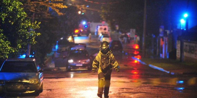 Agente do Bope, utilizando traje de proteção, retornando do veículo onde estavam os explosivos